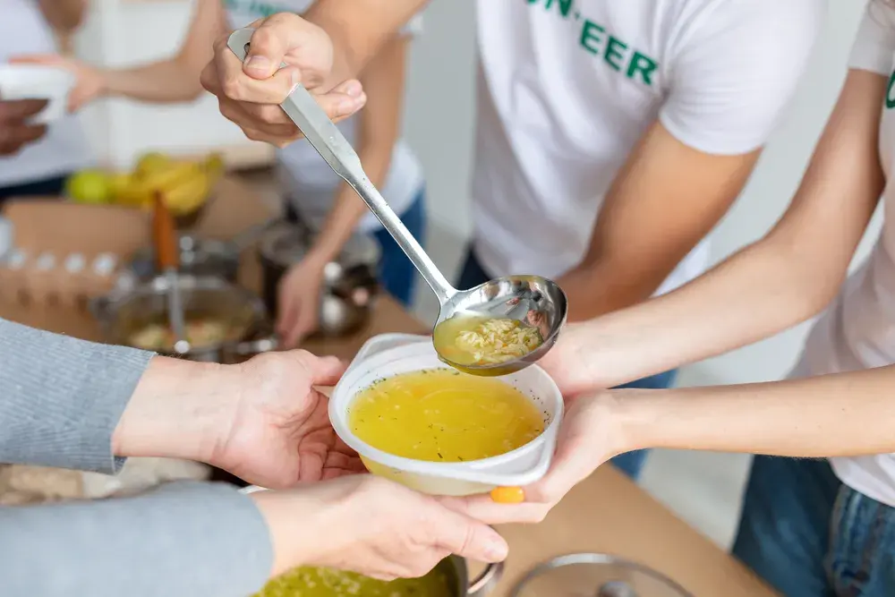 Hands passing a warm meal across a table